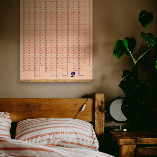 Bedroom with wooden headboard, striped bedding, and a large wall calendar.