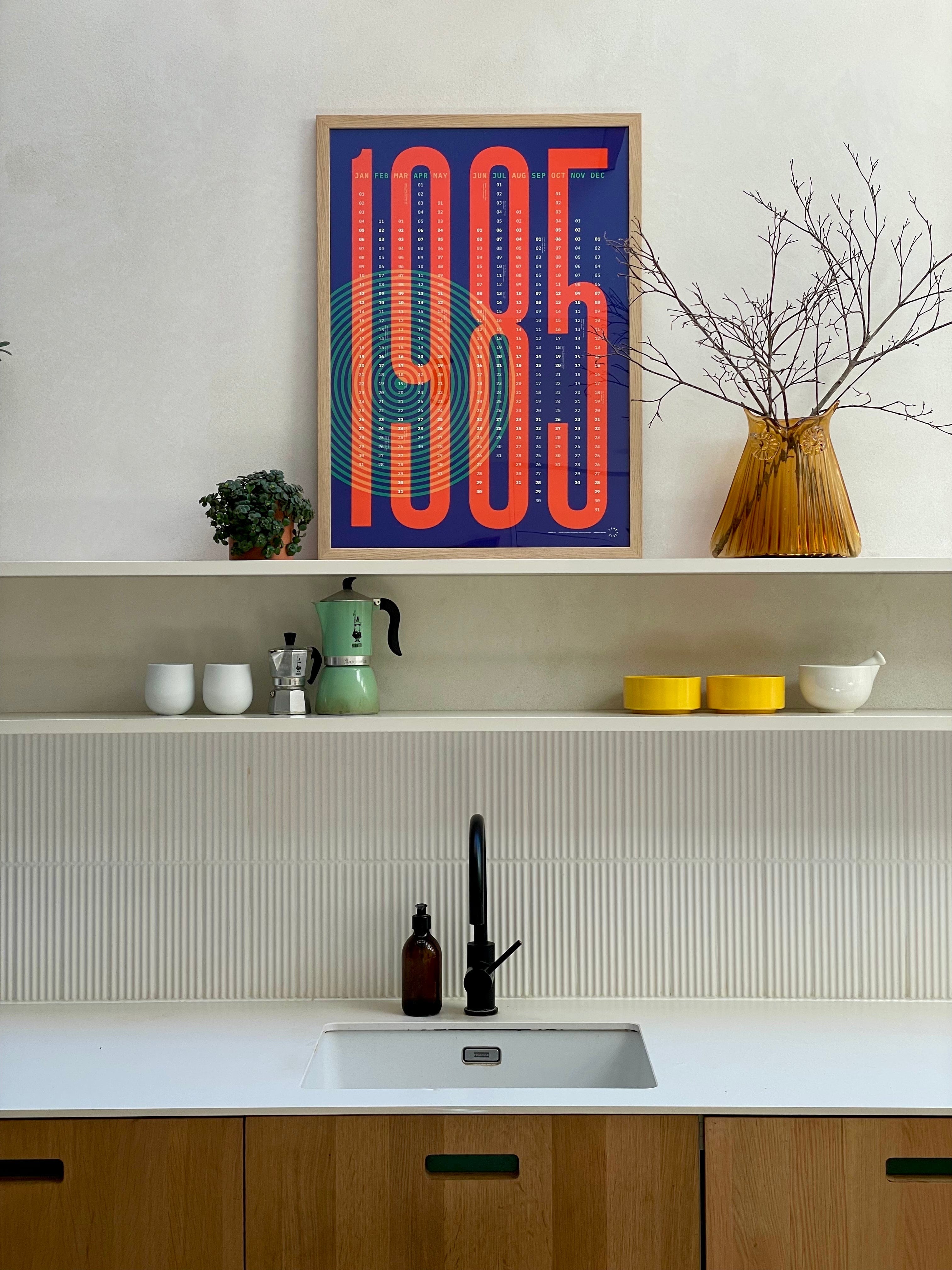Modern kitchen with a '1985' framed poster on the wall.