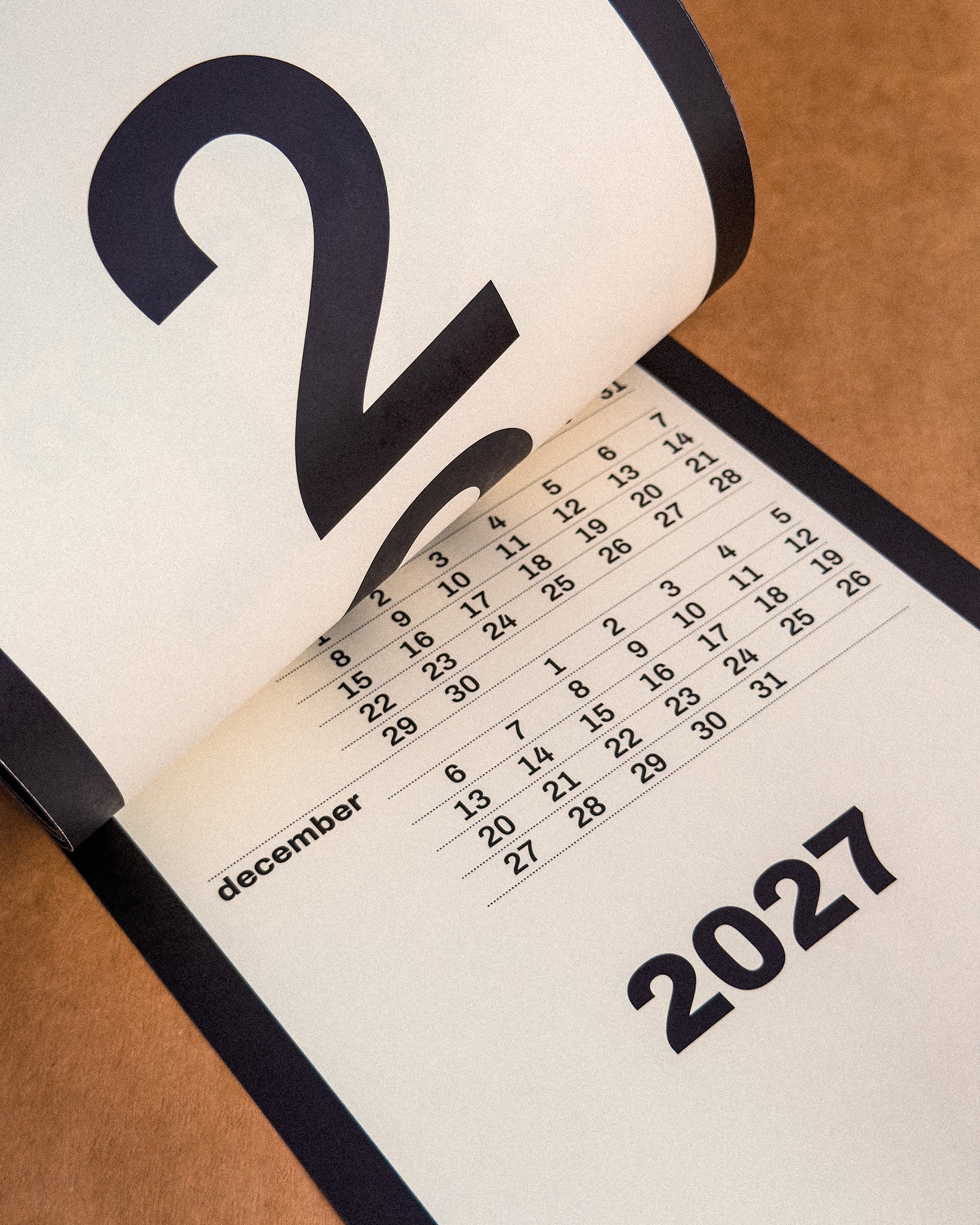 Calendar open to December 2027 on a wooden surface