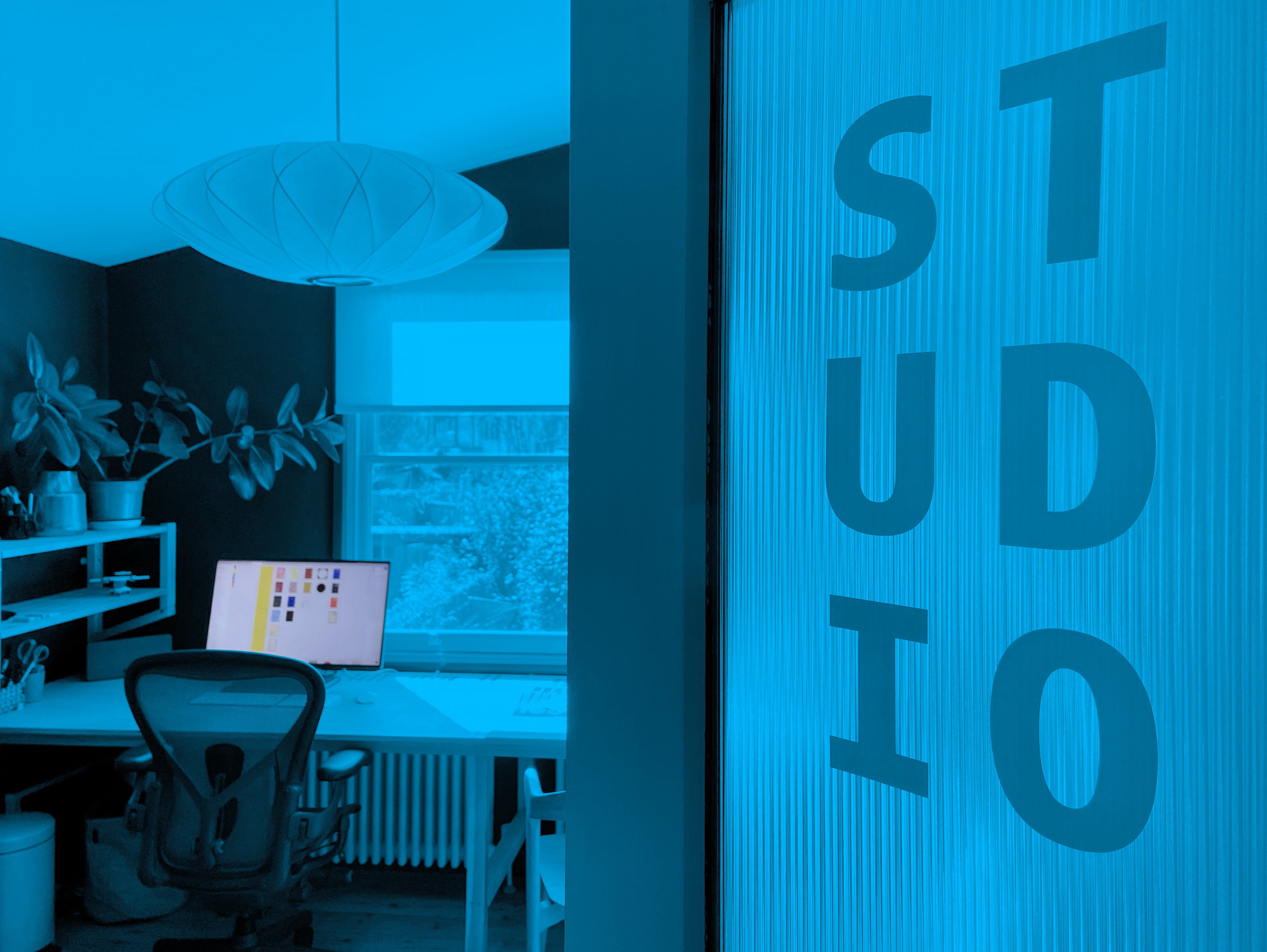 Modern office interior with a desk and computer, featuring a 'STUDIO' sign.